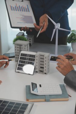 Mimarlar ve iş adamları, emlak sürdürülebilir yatırımları ve güneş enerjisi konut geliştirme projesi için zemin planı modifikasyonunu tartışıyor ve üzerinde kafa yoruyorlar.