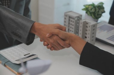 Kask ve yelek tutan inşaat işçileri el sıkışıyor. Emlak konsepti Mimar mühendis veya inşaatçı planlama ve başarılı toplantılarla el sıkışıyor