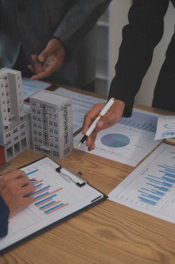 Emlak sektörünü dengelemek. Emlakçı ev tasarımını ve satın alma anlaşmasını görmek için ev tarzını anlatıyor. Modern ofiste ahşap ev.
