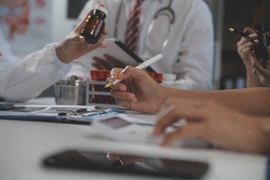 Bir grup profesyonel tıp doktoru, üniforma içinde tıbbi eğitimle buluşuyor. Hasta kayıtlarını tartışıyor ve onlarla konuşuyor, sağlık ekibine öğretiyor, hastanede oturuyor. Sağlık hizmetleri konsepti.