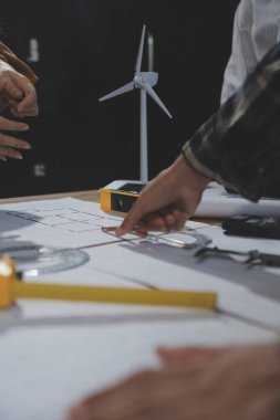 Toplantı odasında inşaat planları üzerinde çalışan çok ırklı mimarlardan oluşan bir ekip. Mühendisler ofiste proje üzerinde tartışıyorlar. Olgun iş adamı ve kadın masanın etrafında durmuş plan üzerinde çalışıyorlar..