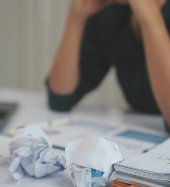 Asian women sitting in a home office With stress and eye strain.Tired businesswoman holding eyeglasses and massaging nose bridge. There are tablets, laptops, and coffee.