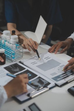 Bir grup profesyonel tıp doktoru, üniforma içinde tıbbi eğitimle buluşuyor. Hasta kayıtlarını tartışıyor ve onlarla konuşuyor, sağlık ekibine öğretiyor, hastanede oturuyor. Sağlık hizmetleri konsepti.