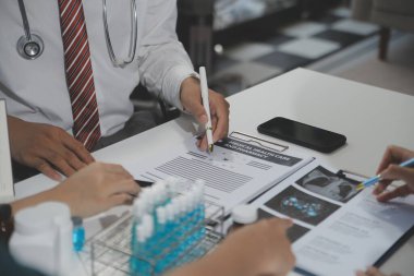 Bir grup profesyonel tıp doktoru, üniforma içinde tıbbi eğitimle buluşuyor. Hasta kayıtlarını tartışıyor ve onlarla konuşuyor, sağlık ekibine öğretiyor, hastanede oturuyor. Sağlık hizmetleri konsepti.