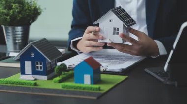 Adam ve emlakçı ev modeli ve model anahtarları tutuyor.