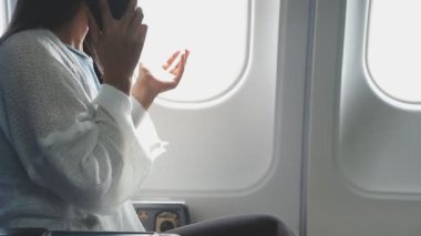 Genç bir kadın telefon kullanıyor ve elinde bir uçak tutuyor.