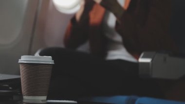 Kadın uçakta oturuyor ve cep telefonu kullanıyor.