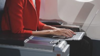 Kırmızı üniformalı bir kadın dizüstü bilgisayarda yazıyor.