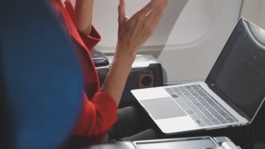 Beyaz gömlekli ve mavi takımlı genç adam uçakta bir dizüstü bilgisayarın başında oturuyor. iş, seyahat ve teknoloji kavramı.