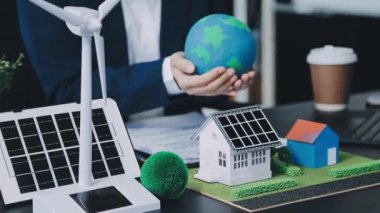 Ofisteki masasında güneş enerjisi olan iş adamı
