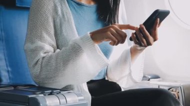 Havaalanında cep telefonu kullanan beyaz ceketli bir kadın.