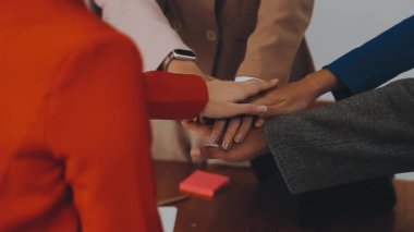 Bir grup iş adamı ofiste el ele tutuşuyor..