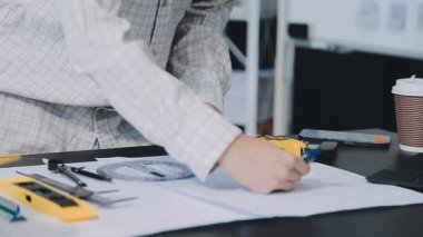 Üniformalı mühendis elektrikli tornavida ve fabrikada aletlerle çalışıyor.