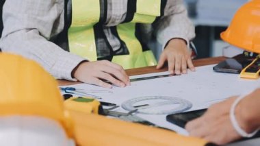 Binanın planlarıyla ya da şantiyesinde çalışan mühendis ya da mimar ya da mühendis.