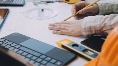 Ofisteki iş yerinde tablet bilgisayar ve planla çalışan genç bir mühendis. mühendislik, inşaat, mimar, mühendislik ve mimari kavramı