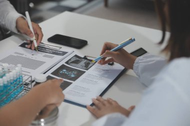 Bir grup profesyonel tıp doktoru, üniforma içinde tıbbi eğitimle buluşuyor. Hasta kayıtlarını tartışıyor ve onlarla konuşuyor, sağlık ekibine öğretiyor, hastanede oturuyor. Sağlık hizmetleri konsepti.