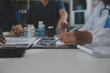 Bir grup profesyonel tıp doktoru, üniforma içinde tıbbi eğitimle buluşuyor. Hasta kayıtlarını tartışıyor ve onlarla konuşuyor, sağlık ekibine öğretiyor, hastanede oturuyor. Sağlık hizmetleri konsepti.