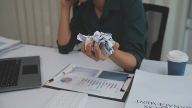Asian women sitting in a home office With stress and eye strain.Tired businesswoman holding eyeglasses and massaging nose bridge. There are tablets, laptops, and coffee.
