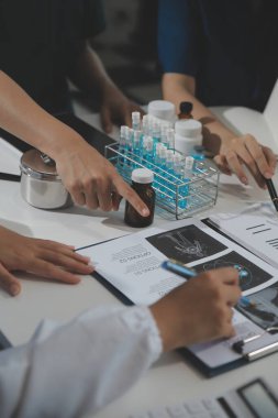 Bir grup profesyonel tıp doktoru, üniforma içinde tıbbi eğitimle buluşuyor. Hasta kayıtlarını tartışıyor ve onlarla konuşuyor, sağlık ekibine öğretiyor, hastanede oturuyor. Sağlık hizmetleri konsepti.