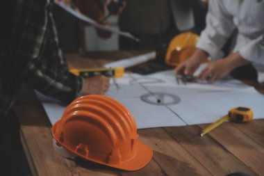 Toplantı odasında inşaat planları üzerinde çalışan çok ırklı mimarlardan oluşan bir ekip. Mühendisler ofiste proje üzerinde tartışıyorlar. Olgun iş adamı ve kadın masanın etrafında durmuş plan üzerinde çalışıyorlar..