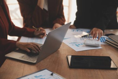 Group of confident business people point to graphs and charts to analyze market data, balance sheet, account, net profit to plan new sales strategies to increase production capacity.