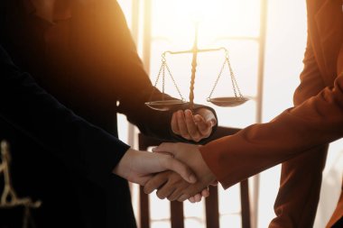 Avukat, müvekkil ile evraklar, sözleşmeler, anlaşmalar, iş birliği anlaşmaları hakkında el sıkışıyor avukatın masasında bir kadın müvekkil ve masada bir çekiç.