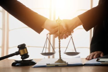 Avukat, müvekkil ile evraklar, sözleşmeler, anlaşmalar, iş birliği anlaşmaları hakkında el sıkışıyor avukatın masasında bir kadın müvekkil ve masada bir çekiç.