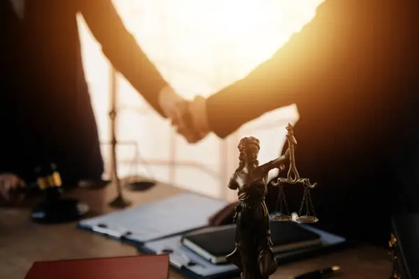 Lawyer shaking hands with a client making about documents, contracts, agreements, cooperation agreements with a female client at the lawyer\'s desk and a hammer at the table.
