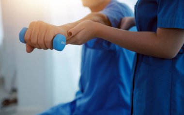 Egzersiz halter tedavi hakkında kol ve omuz sporcu ile erkek hastanın fizik tedavi kavramı veren fizyoterapist adam