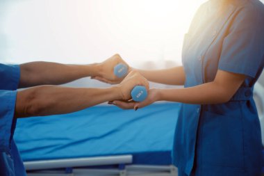 Egzersiz halter tedavi hakkında kol ve omuz sporcu ile erkek hastanın fizik tedavi kavramı veren fizyoterapist adam