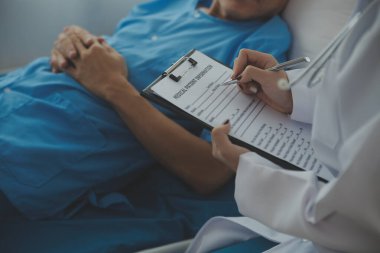 Doktor nabzını kontrol ederken hastanede yatan bir adam. Kadın doktor, erkek hastayı hastane odasında muayene ediyor..