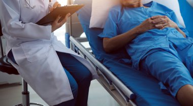 Doktor nabzını kontrol ederken hastanede yatan bir adam. Kadın doktor, erkek hastayı hastane odasında muayene ediyor..