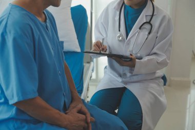 Genç bayan doktor ve hemşireler hastanede konsültasyon yapan yaşlı ve mutlu erkek hastalarla konuşmaya yardım ediyorlar. Değer veren, cesaretlendiren ve olgun erkekleri rahatlatan. sağlık hizmeti kavramı