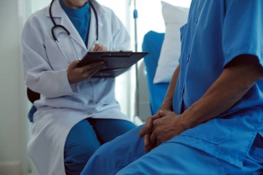 Genç bayan doktor ve hemşireler hastanede konsültasyon yapan yaşlı ve mutlu erkek hastalarla konuşmaya yardım ediyorlar. Değer veren, cesaretlendiren ve olgun erkekleri rahatlatan. sağlık hizmeti kavramı