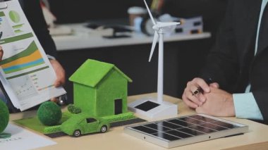 Genç işadamı masasında yeşil enerji modeli olan tablet kullanıyor..