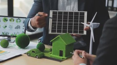 İş adamı elinde bir modelle güneş enerjisi paneli tutuyor