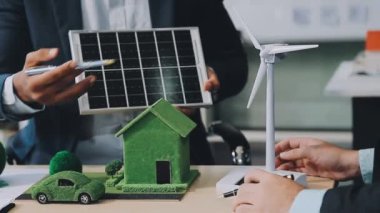 İş adamı ev modelinde güneş enerjisi panelleri tutuyor.