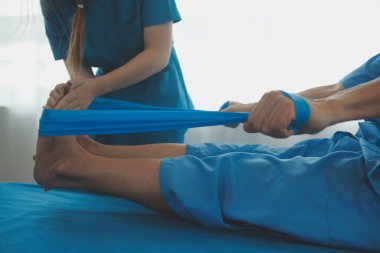 Klinikteki küçük hastanın bacağını muayene eden profesyonel bir ortopedist. Fizyoterapideki hasta terapistiyle fiziksel egzersiz yapıyor.