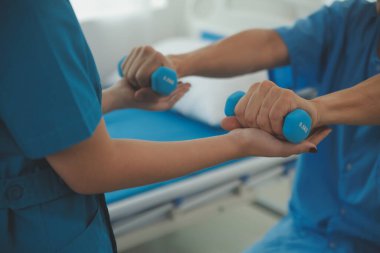 Egzersiz halter tedavi hakkında kol ve omuz sporcu ile erkek hastanın fizik tedavi kavramı veren fizyoterapist adam