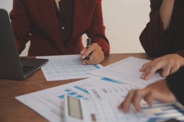 Group of confident business people point to graphs and charts to analyze market data, balance sheet, account, net profit to plan new sales strategies to increase production capacity.