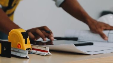 Sarı gömlekli ve kot pantolonlu, mezuralı ve kalemli bir işçi..