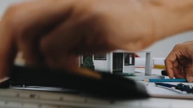 Beyaz bir evin önünde elinde bina planlı bir model tutan bir mühendis. Mühendislik ve mimarlık kavramı.