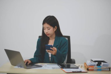 Bilgisayarı ve akıllı telefonu kullanan çekici Asyalı kadın..