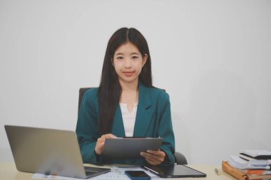 Asyalı iş kadını dizüstü bilgisayarla çalışıyor, pazarlama raporu ve hesap makinesi dokümanı masanın üzerinde, finansal raporları analiz etmek için online iş planına, e-ticarete yatırım yapıyor..