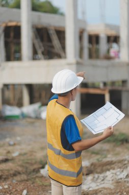 İnşaat alanındaki Mühendislik Danışmanlığı elinde planları tutuyor. İnşaat müfettişi. Yeni binanın inşaat sahası çizimi ve iş akışı