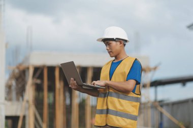 Dizüstü bilgisayarı tutan işçi ya da mühendis ve deponun içindeki konteynırları kontrol ediyor