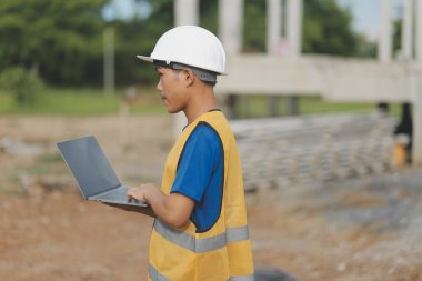 Dizüstü bilgisayarı tutan işçi ya da mühendis ve deponun içindeki konteynırları kontrol ediyor
