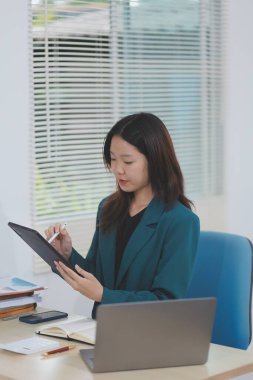 Şirket ofisinde tablet bilgisayarda çalışan Asyalı profesyonel iş kadını.