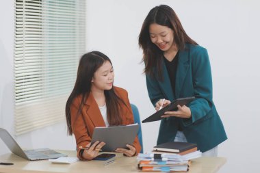 İki genç Asyalı iş kadını yatırım projesinin çalışma ve planlama stratejisini tartıştı. İş adamları ofiste dizüstü bilgisayarla konuşuyor..