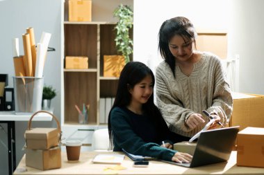 Başlangıçta küçük işletme KOBİ 'si, akıllı telefon veya tablet kullanan girişimci Afrikalı kadın paket ürün kutusu hazırlamak için çevrimiçi alışveriş siparişini alır ve kontrol eder.